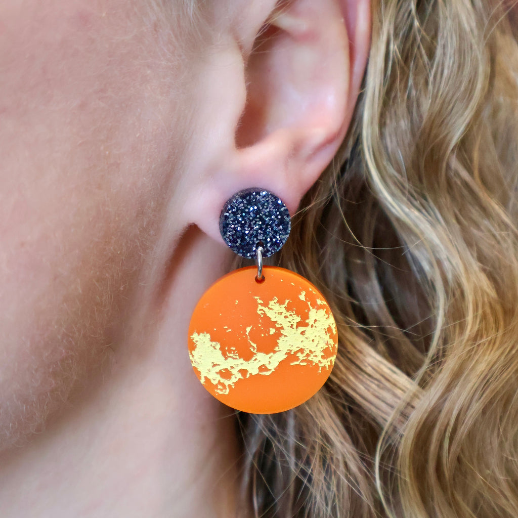Laser cut acrylic Venus earrings being modelled. 