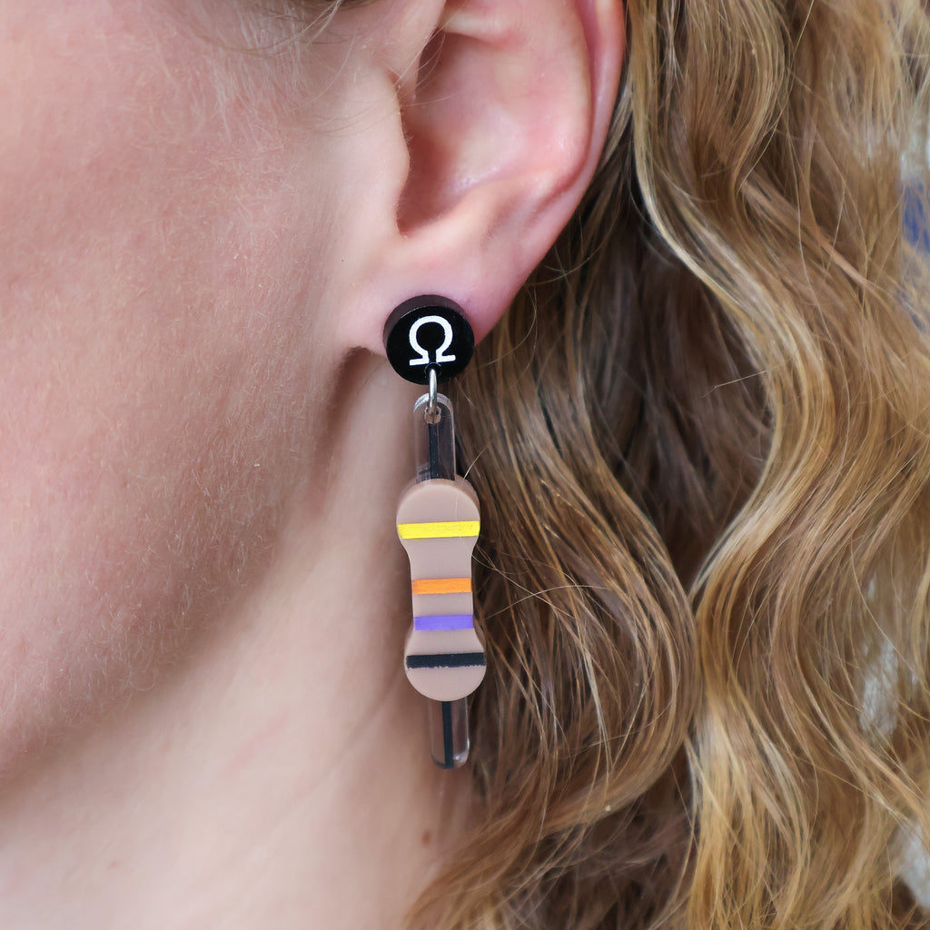 Laser cut acrylic resistor earrings being modelled.