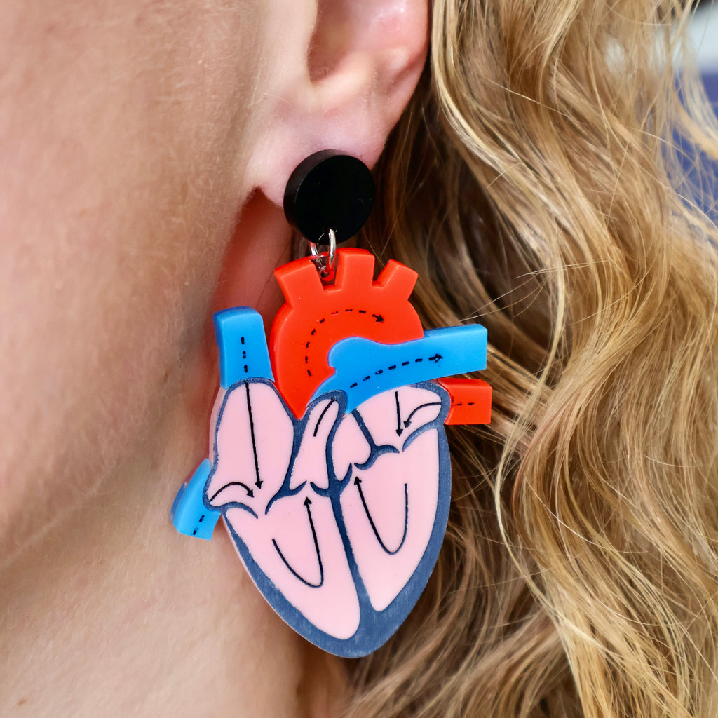 Anatomical heart earrings, showing a cross-sectional view. Made from laser cut and handpainted acrylic. Earrings are being modelled.