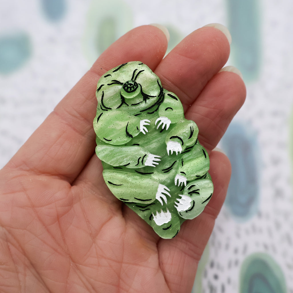 Green acrylic tardigrade brooch in hand for scale