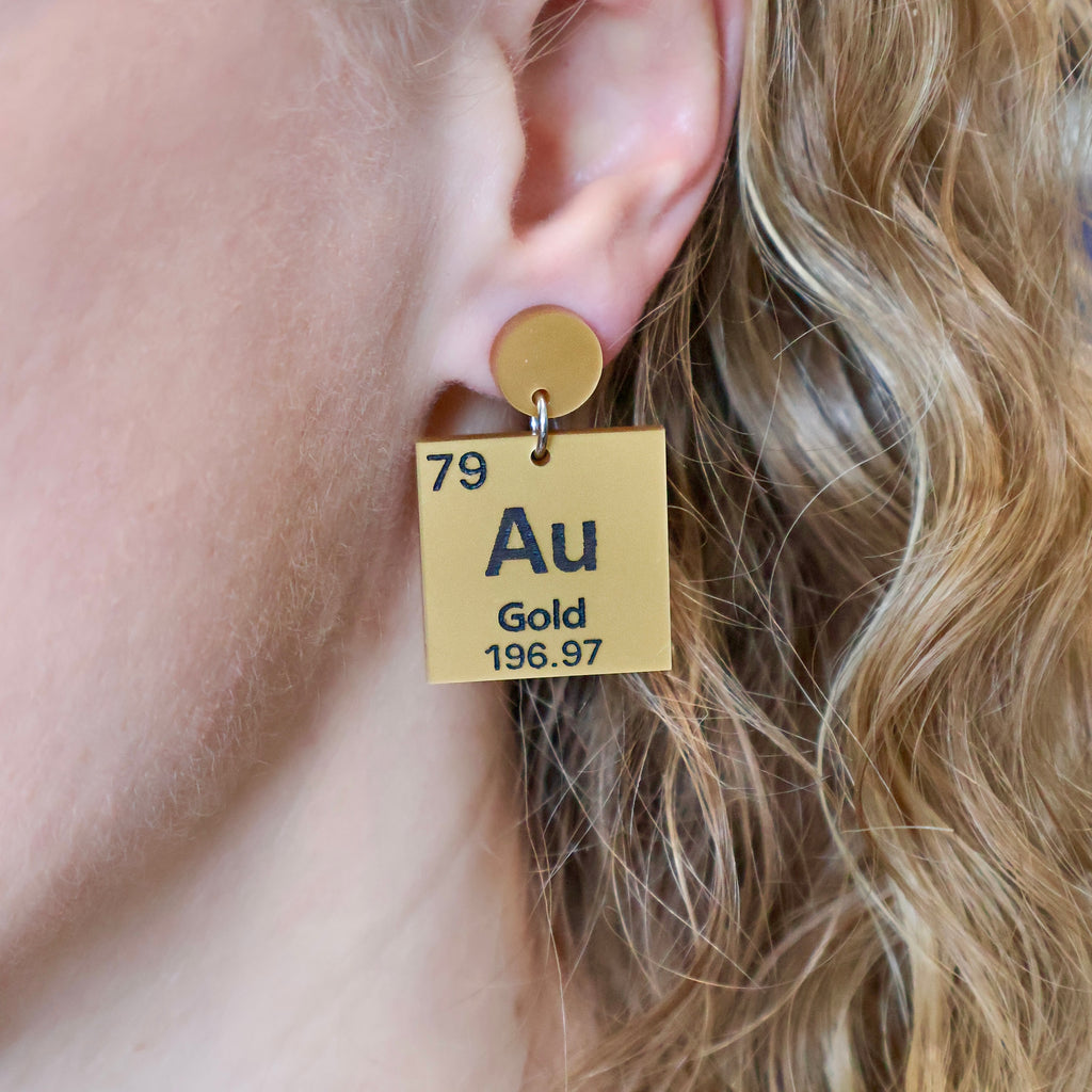 Gold periodic table earrings being modelled. 