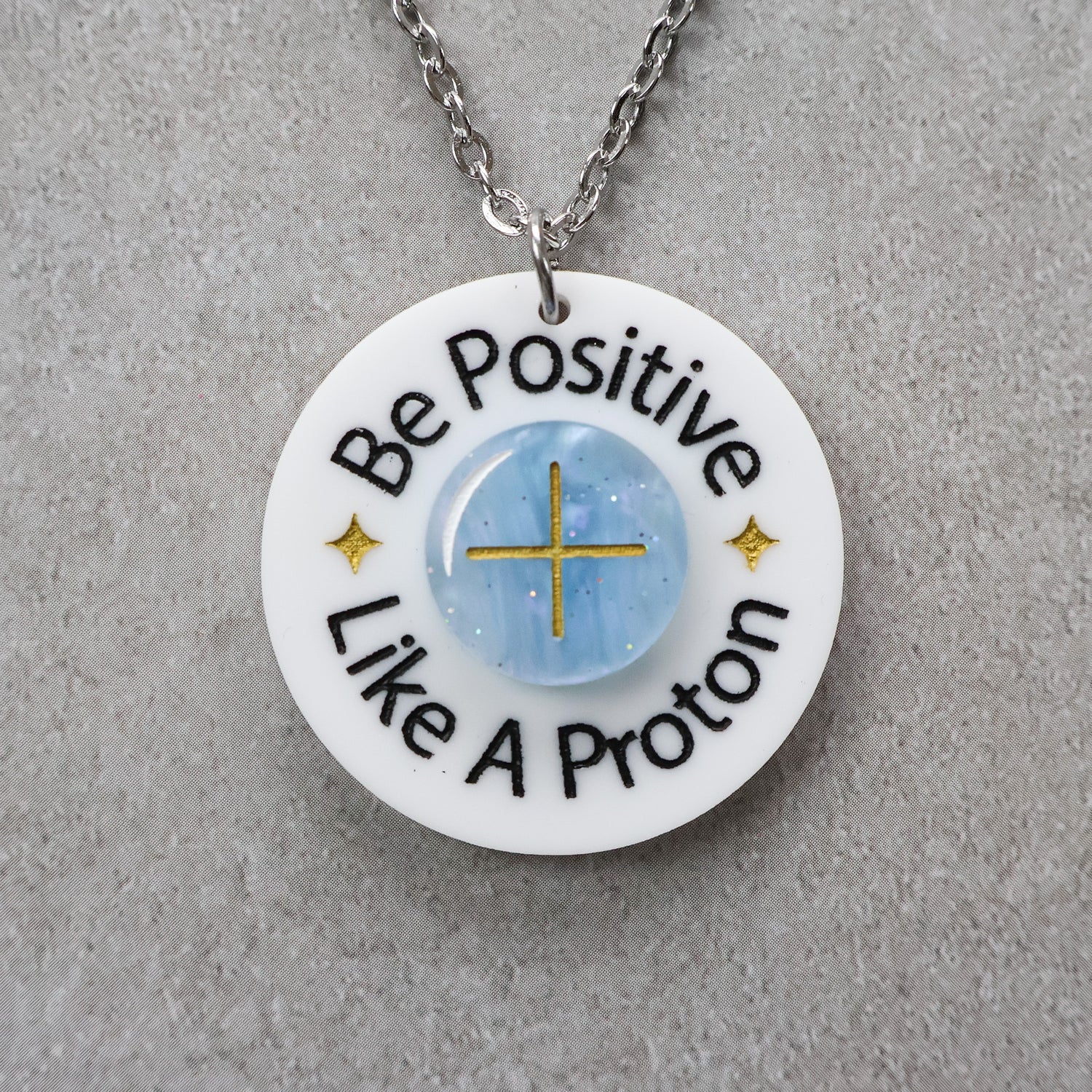 Necklace with a pendant that says 'Be Positive Like A Proton'