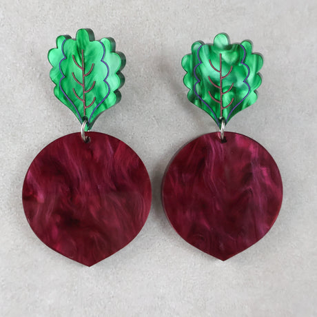Pair of acrylic beetroot earrings with green leaf-shaped tops and marbled maroon circular bodies on a light grey background