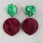 Pair of acrylic beetroot earrings with green leaf-shaped tops and marbled maroon circular bodies on a light grey background