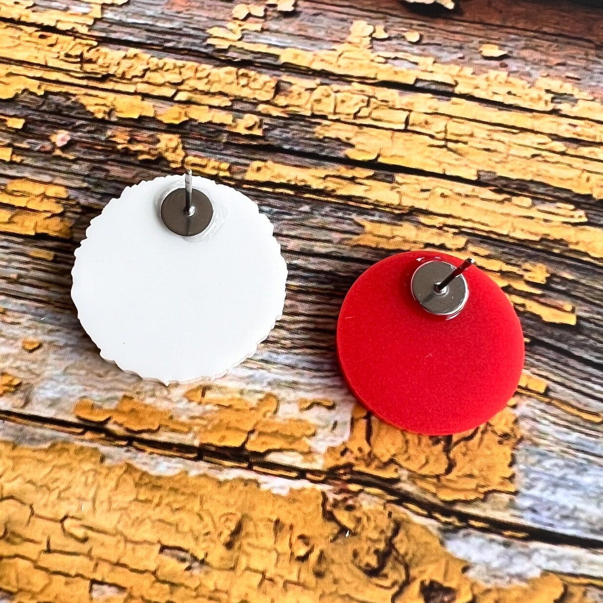 A pair of asymmetrical studs. One side is a red blood cell while the other side is a larger white blood cell. Laser cut, and handpainted from acrylic. Back view showing the stainless steel earring posts.