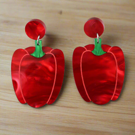 Red pepper or capsicum-shaped marbled acrylic earrings on a light grey background