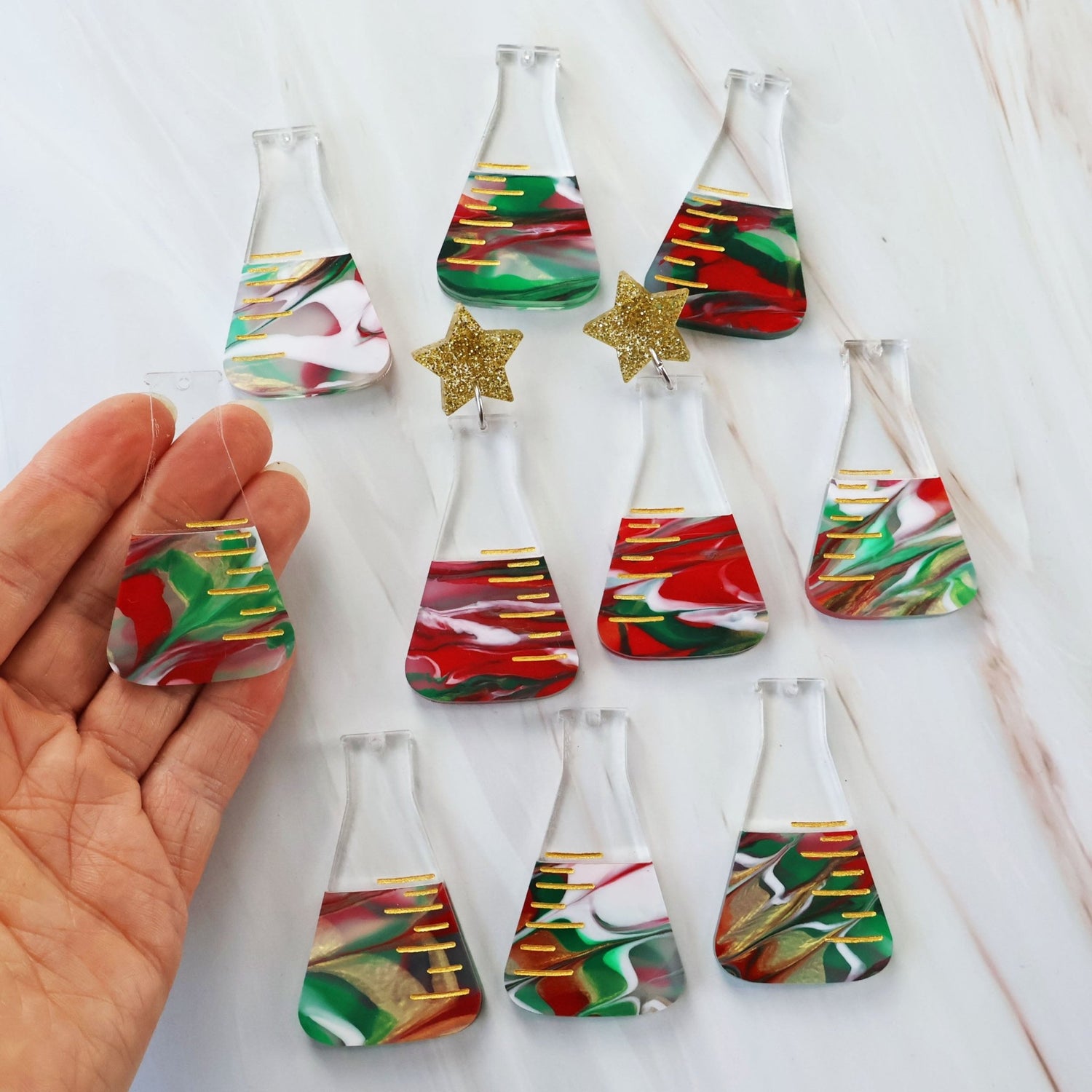 Photo showing the variation in colours across different pairs of dangle earrings featuring a conical flask design with Christmas-themed decorations.