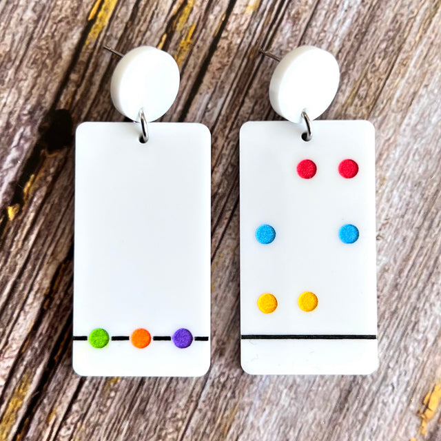 A pair of Chromatography earrings featuring white rectangular shapes with a series of colorful dots arranged in a specific pattern, hanging from white toppers.