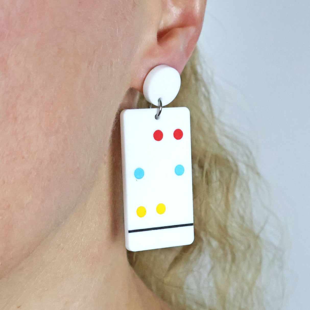 Chromatography Earrings with colourful dots worn by a person against a neutral background