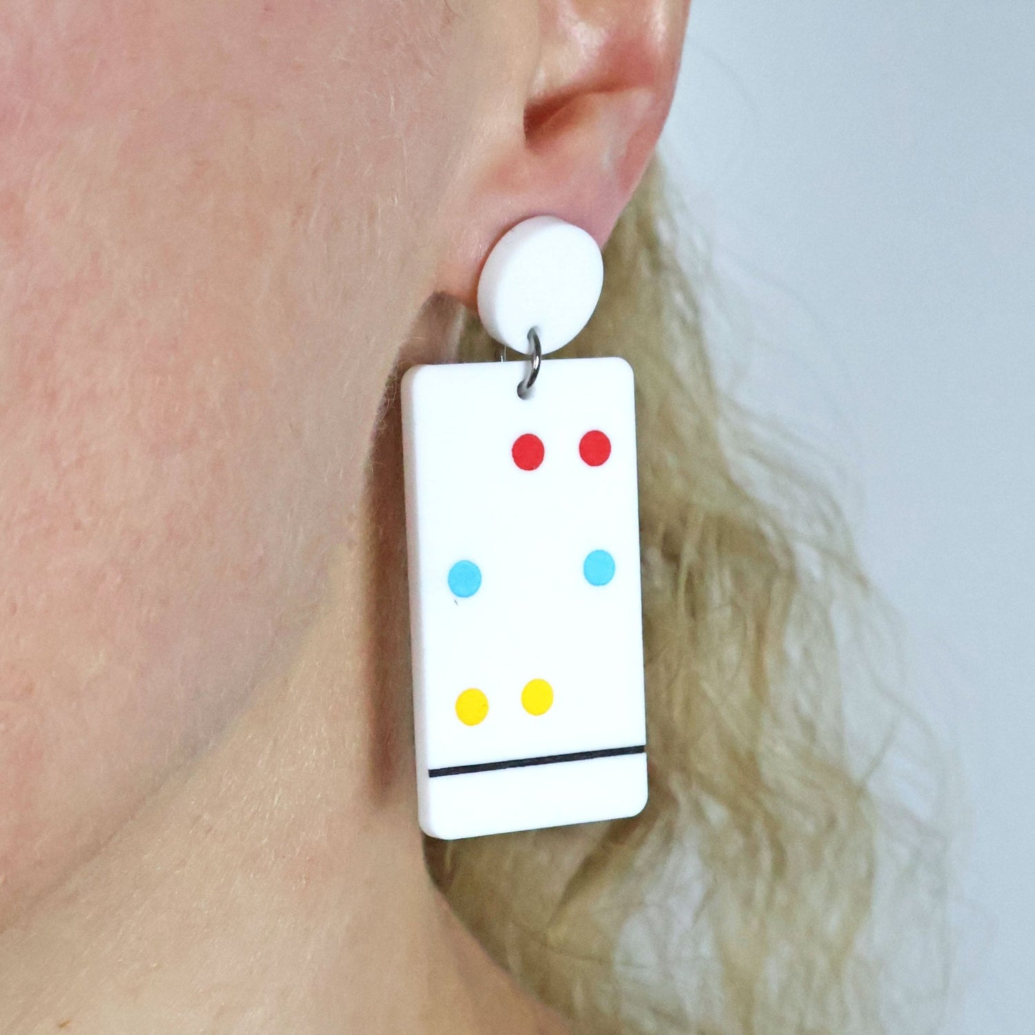 Chromatography Earrings with colourful dots worn by a person against a neutral background