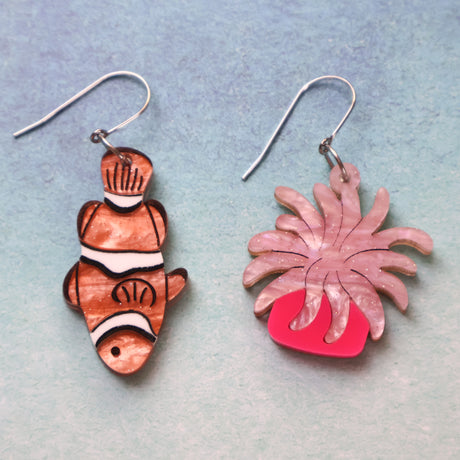 An asymmetrical pair of acrylic earrings with an orange clownfish n one side and a pink sea anemone on the other. Topped with stainless steel french hooks.