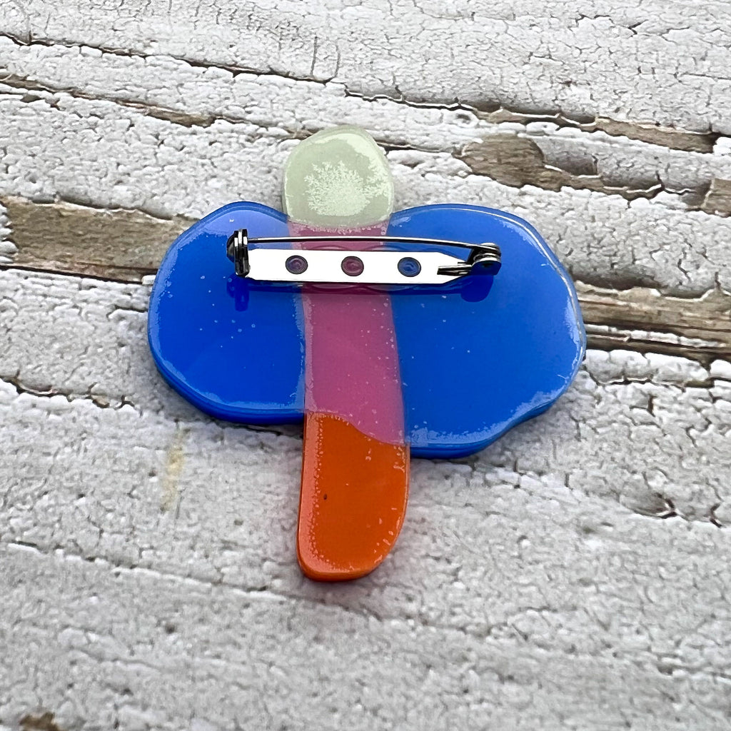 The back of an acrylic dragonfly brooch, showing the stainless steel brooch pin and rolling clasp.