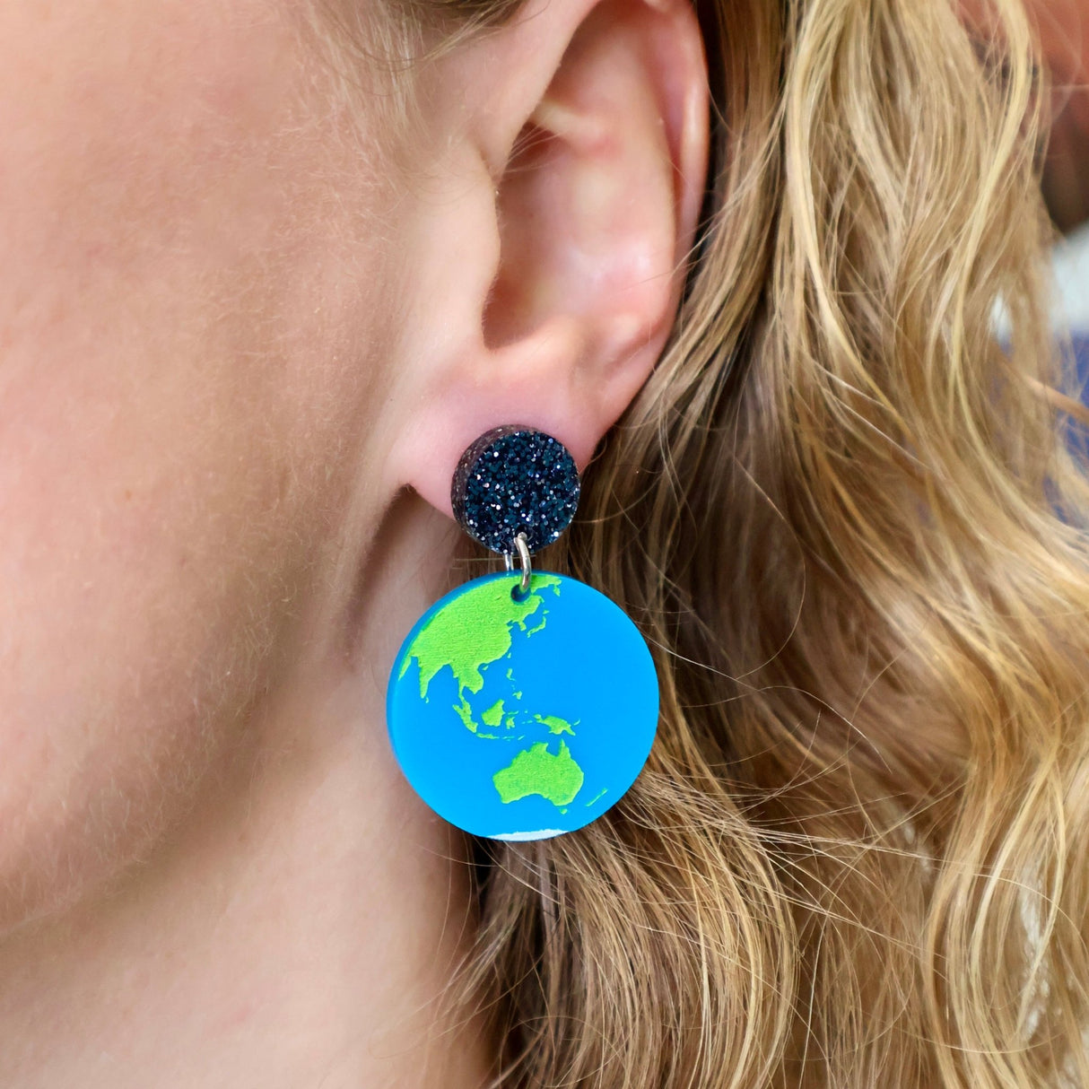 Acrylic earth earring being modelled. Not shown is the asymmetrical moon earrings that comprises the other half of the pair.