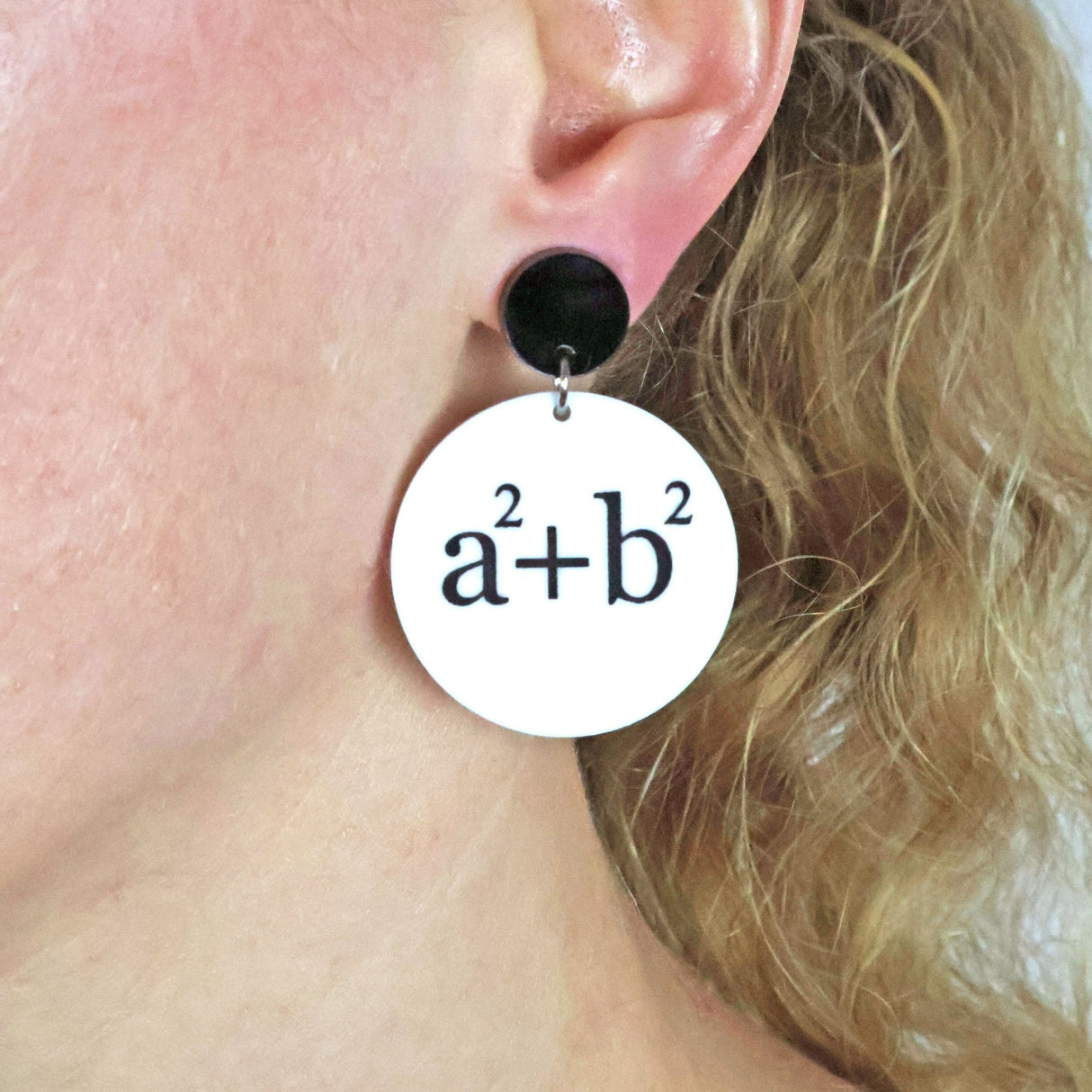 Acrylic round dangle earrings with the mathematical formula 'a^2 + b^2 = c^2' being modelled by a person.