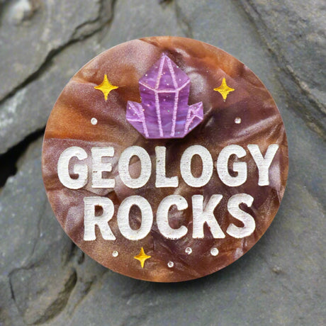 Acrylic brooch with 'Geology Rocks' text and a purple crystal design