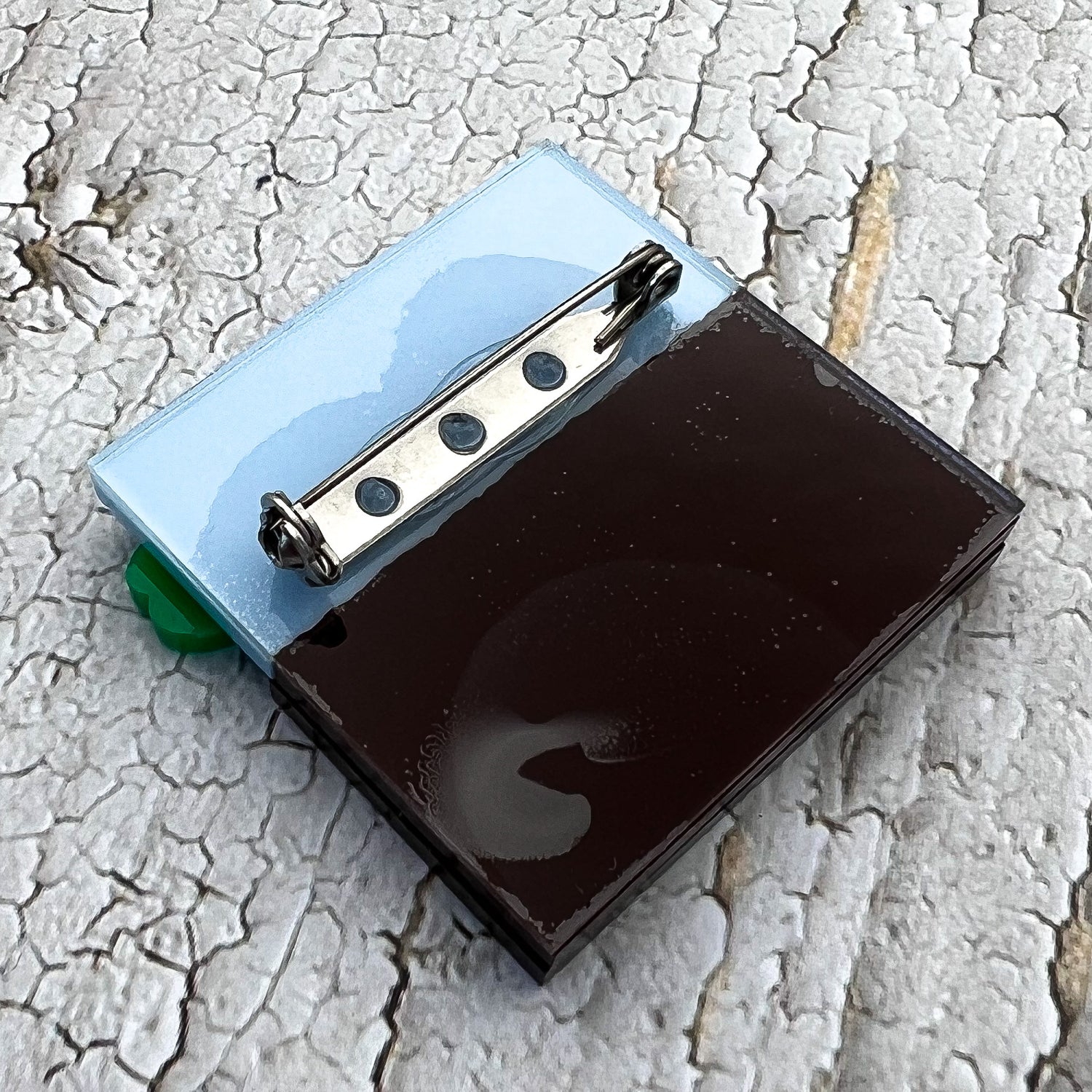 The back view of a germination acrylic brooch, showing the stainless steel brooch pin and rolling clasp.