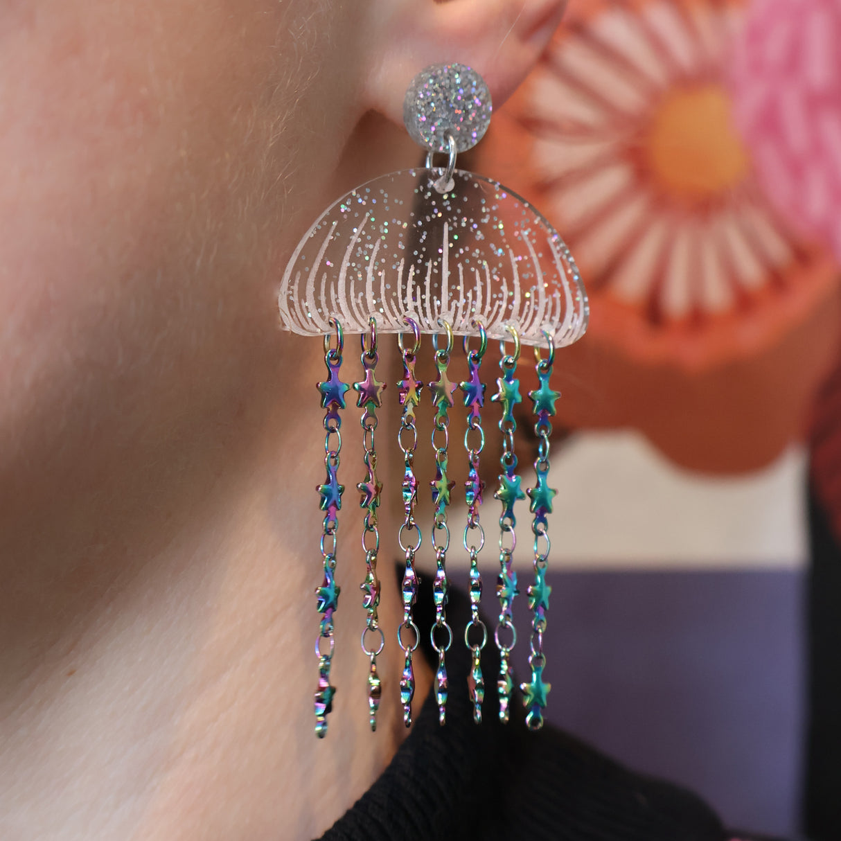 Glittery Acrylic jellyfish earrings with rainbow star chain, being modelled.