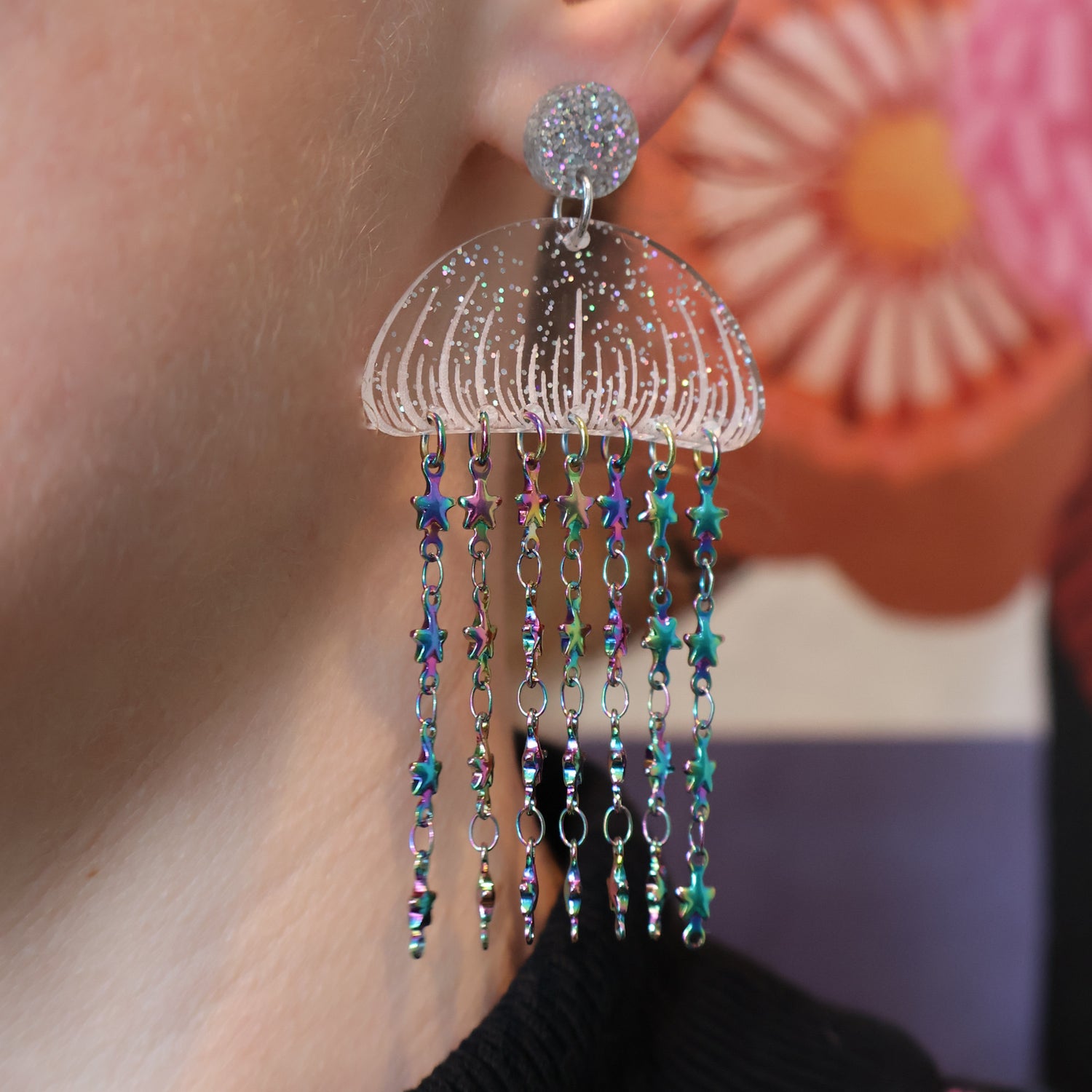 Glittery Acrylic jellyfish earrings with rainbow star chain, being modelled.