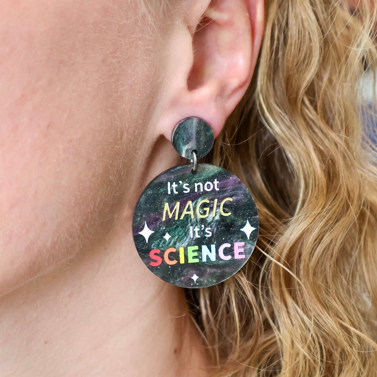 Round dangle earrings with "It's not Magic It's Science' engraved and handpainted within. Made from laser cut swirly acrylic. Earrings are being modelled.