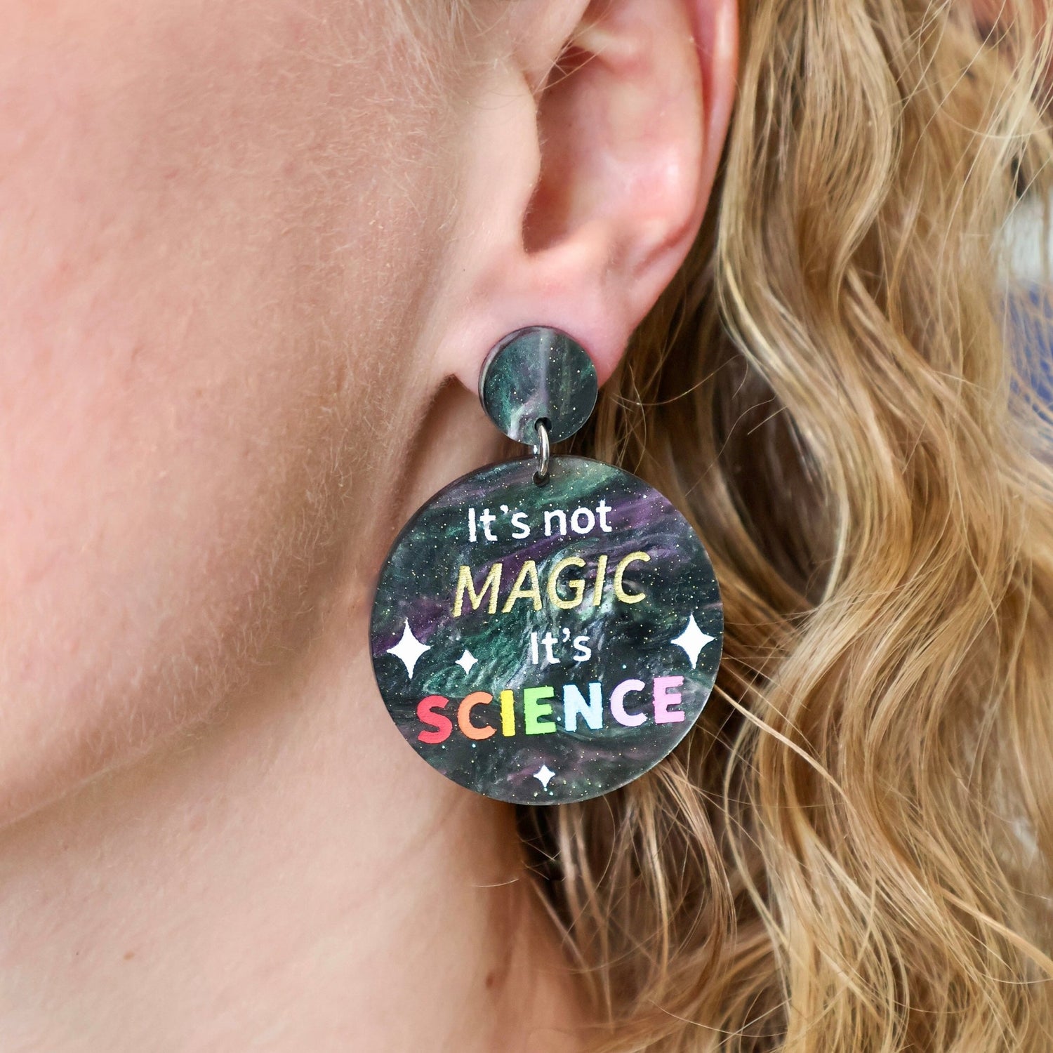 Round dangle earrings with "It's not Magic It's Science' engraved and handpainted within. Made from laser cut swirly acrylic. Earrings are being modelled.
