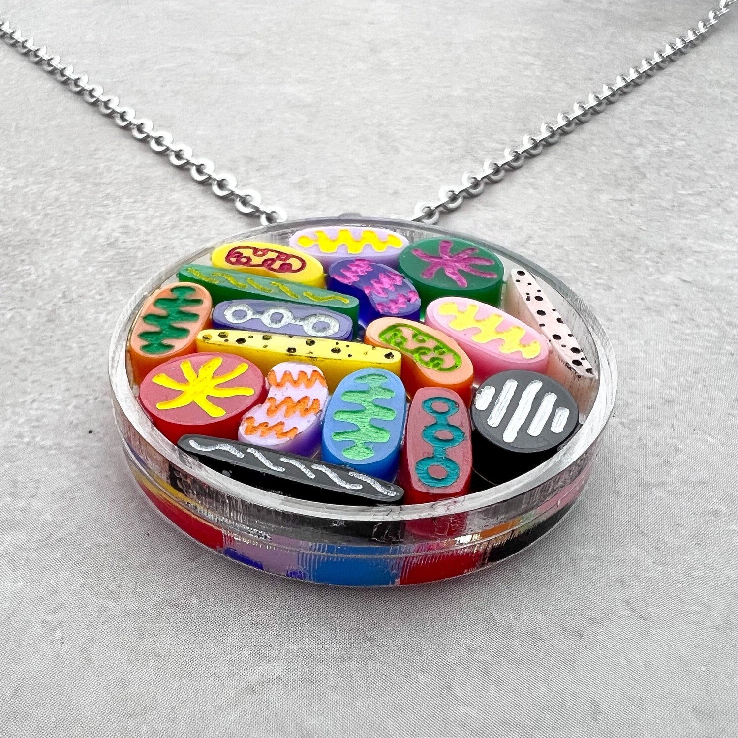 Necklace with colorful Petri dish acrylic pendant on a gray background