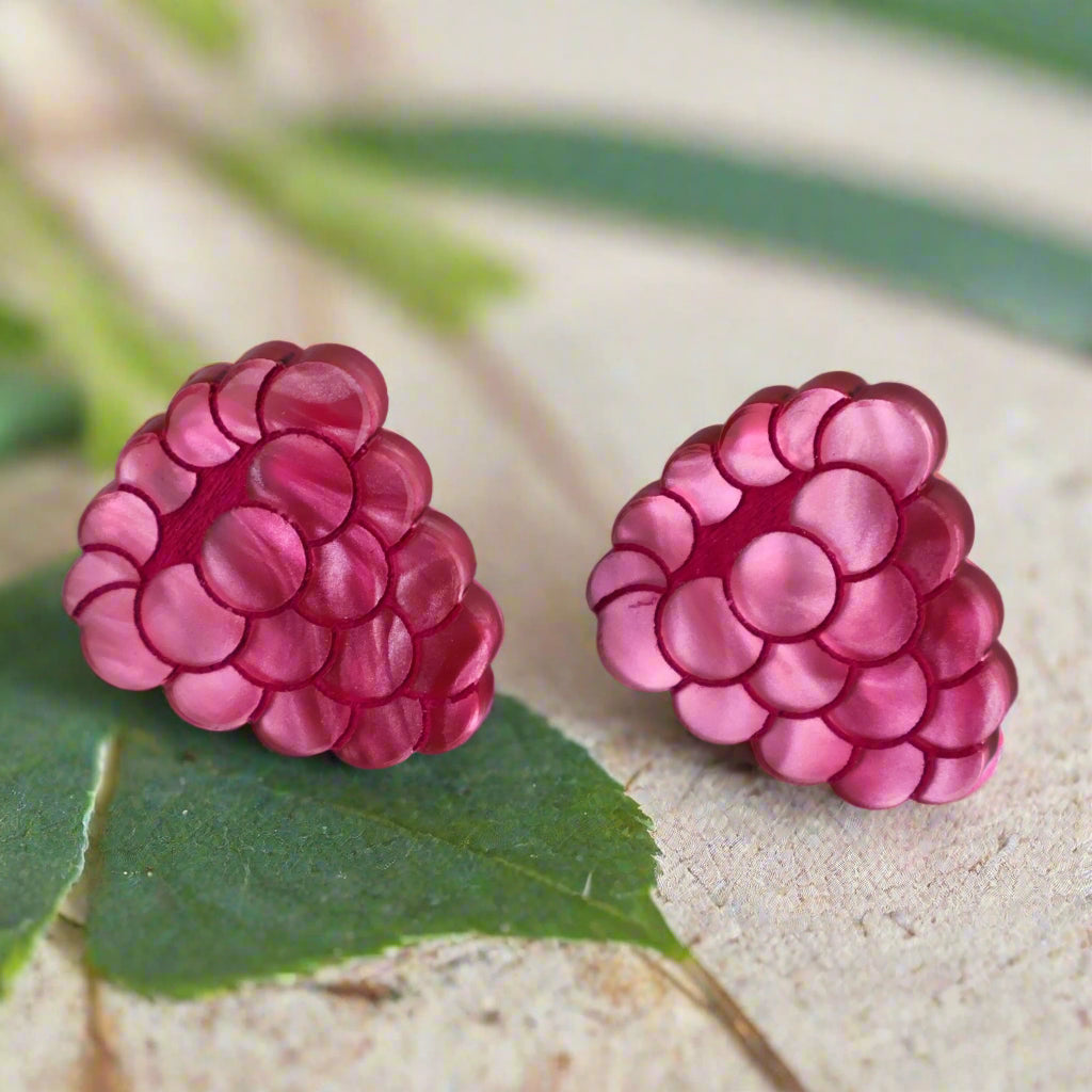 Pink marbled acrylic raspberry-shaped earrings on a grey background