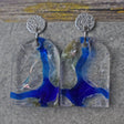 A pair of one of a kind arch shaped recycled acrylic earrings with blue, clear and pearlescent acrylics titled  'Aurora Shards' and stainless steel toppers. Pair 100-07