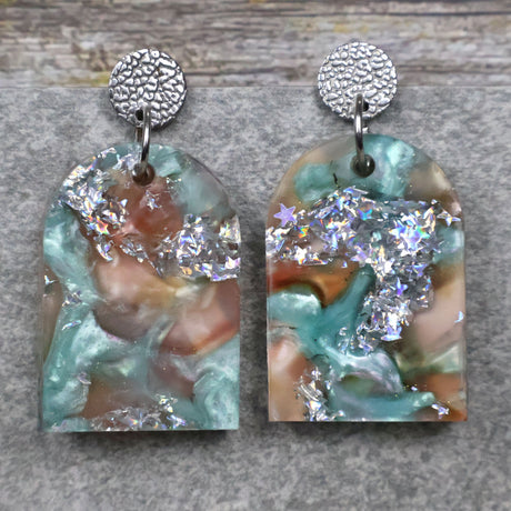 A pair of one of a kind arch shaped recycled acrylic earrings with silver, green and brown design titled 'Celestial Tide' and stainless steel toppers. Pair 102-03