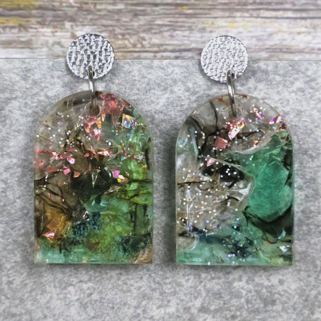 A pair of one of a kind arch shaped recycled acrylic earrings with green and pink design titled 'Enchanted Forest' and stainless steel toppers. Pair 103-02
