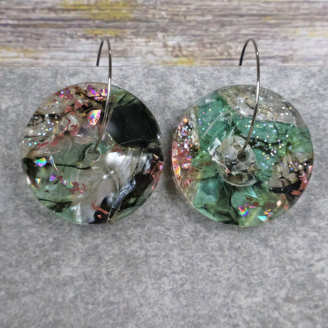 A pair of one of a kind disc shaped recycled acrylic earrings on stainless steel hoops with green and pink acrylics titled 'Enchanted Forest'. Pair 03-10