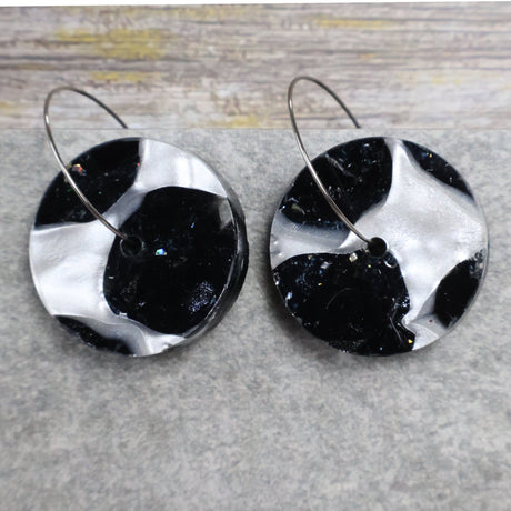 A pair of one of a kind recycled acrylic disc shaped earrings on stainless steel hoops with multicolored design titled 'Lunar Edge'. Pair 104-07
