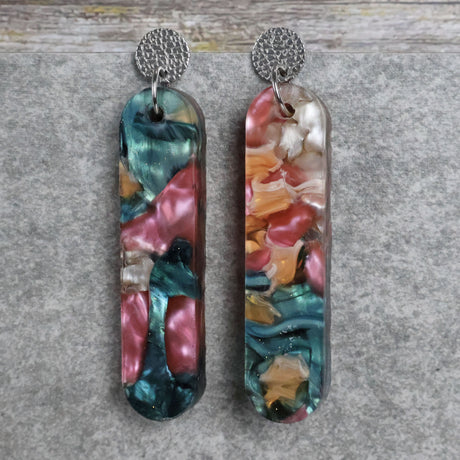 Pair of one of a kind long bar shaped acrylic earrings with multicolored  design titled 'Sunset Reef' and stainless steel toppers on a gray background. Pair 106-07