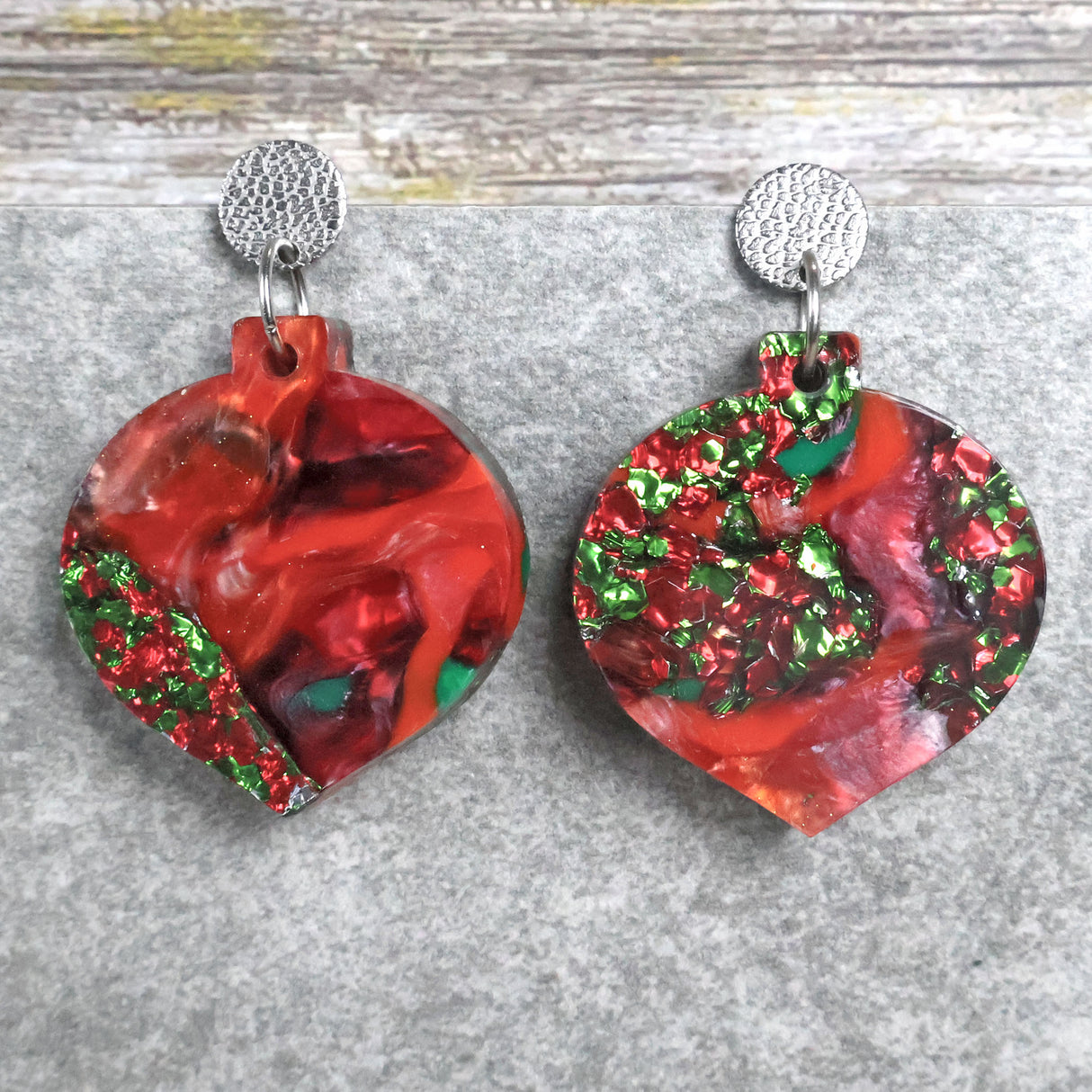 A pair of one of a kind recycled acrylic Christmas bauble earrings with stainless steel toppers, featuring a red, green and gold acrylic design. Pair 107-01
