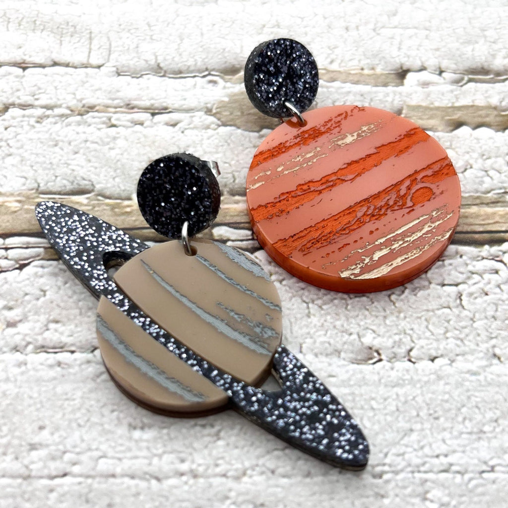 A pair of asymmetrical earrings, of Jupiter and Saturn. Laser cut from acrylic with handpainted details. 