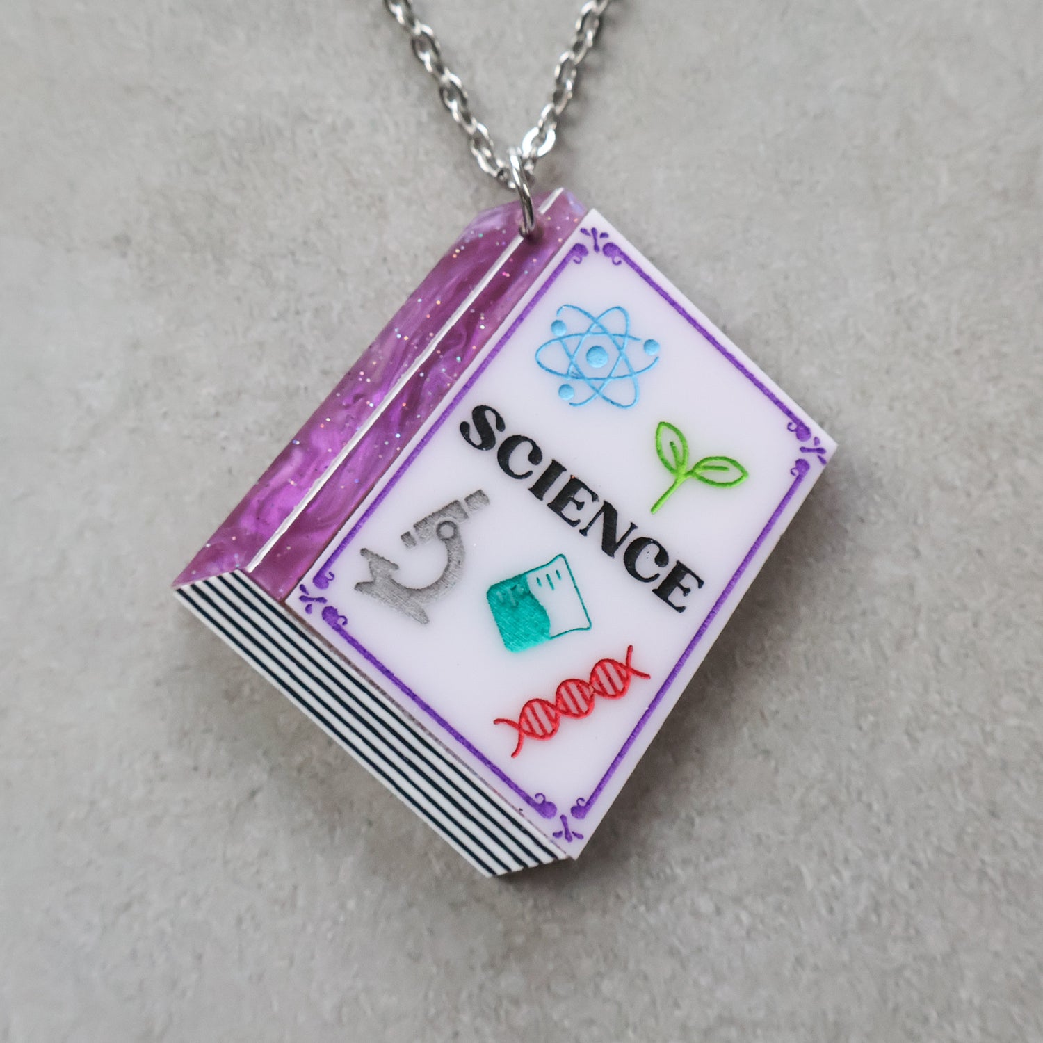Closeup of a necklace with a science-themed textbook pendant