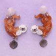 A pair of acrylic earrings with sea otter design on a light blue background