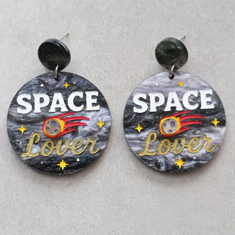 Earrings with 'Space Lover' design on a gray background with a meteor