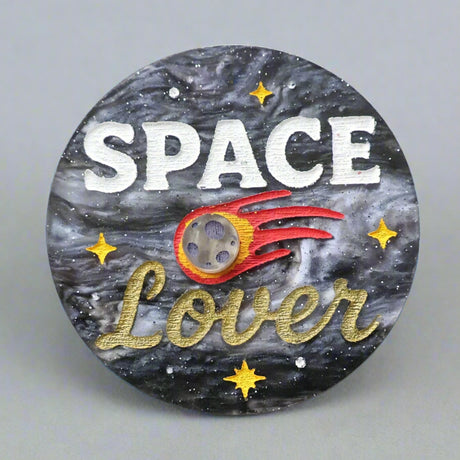 Circular acrylic brooch with 'Space Lover' text and space-themed design with a meteor