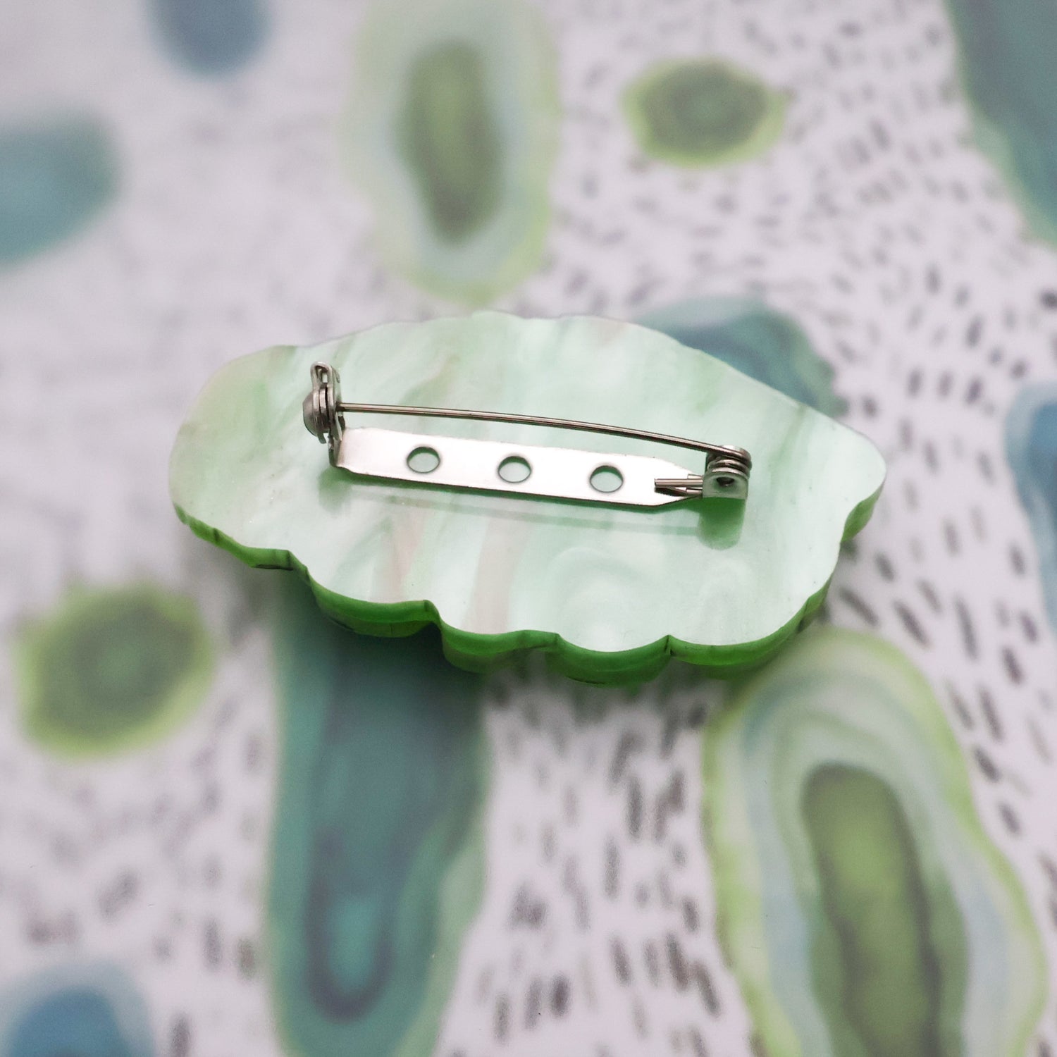 Back of green acrylic tardigrade brooch showing stainless steel brooch pin