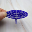 Closeup of dark blue acrylic wormhole brooch, with white handpainted detailing, depicting the warping of spacetime.