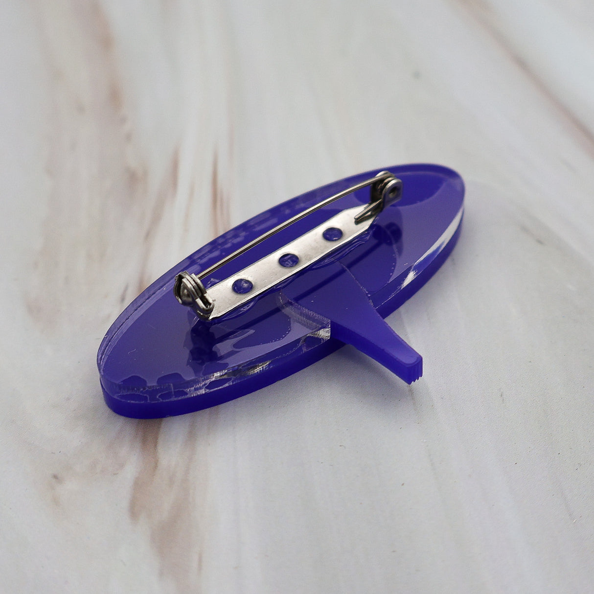 Back view of dark blue wormhole brooch, showing the stainless steel brooch pin with rolling clasp.