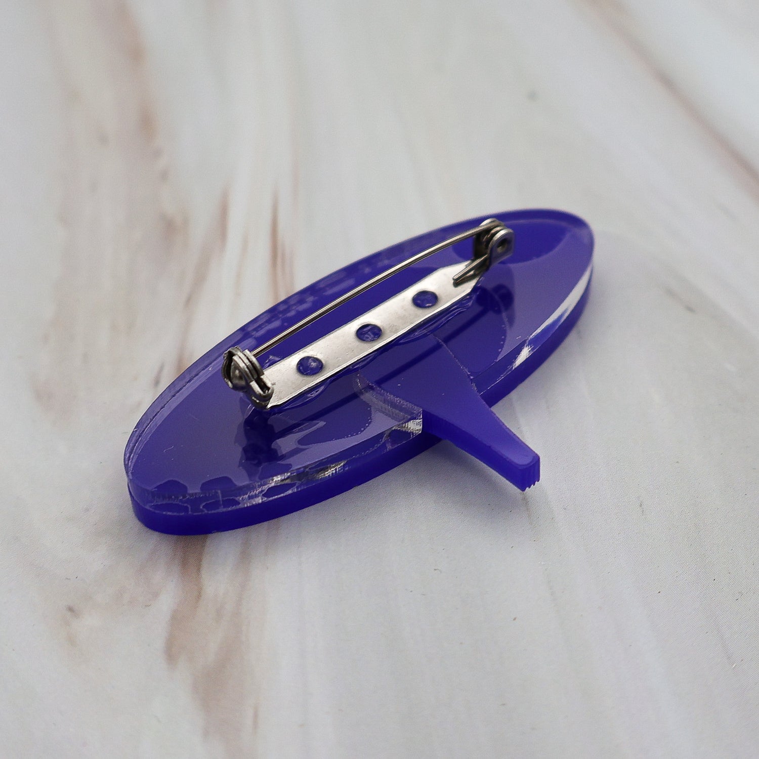 Back view of dark blue wormhole brooch, showing the stainless steel brooch pin with rolling clasp.