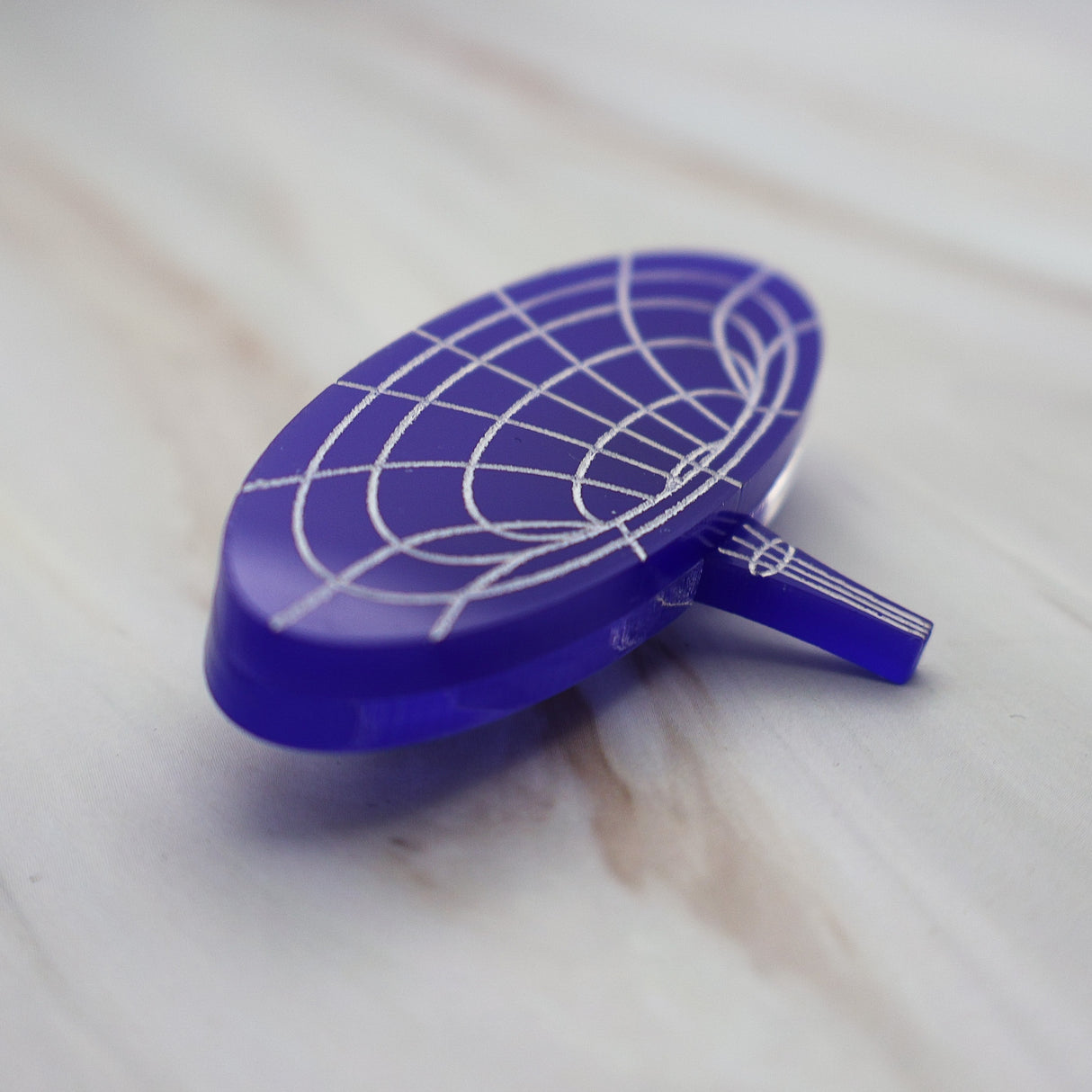 Angled view of dark blue wormhole brooch showing it's multilayered consruction.