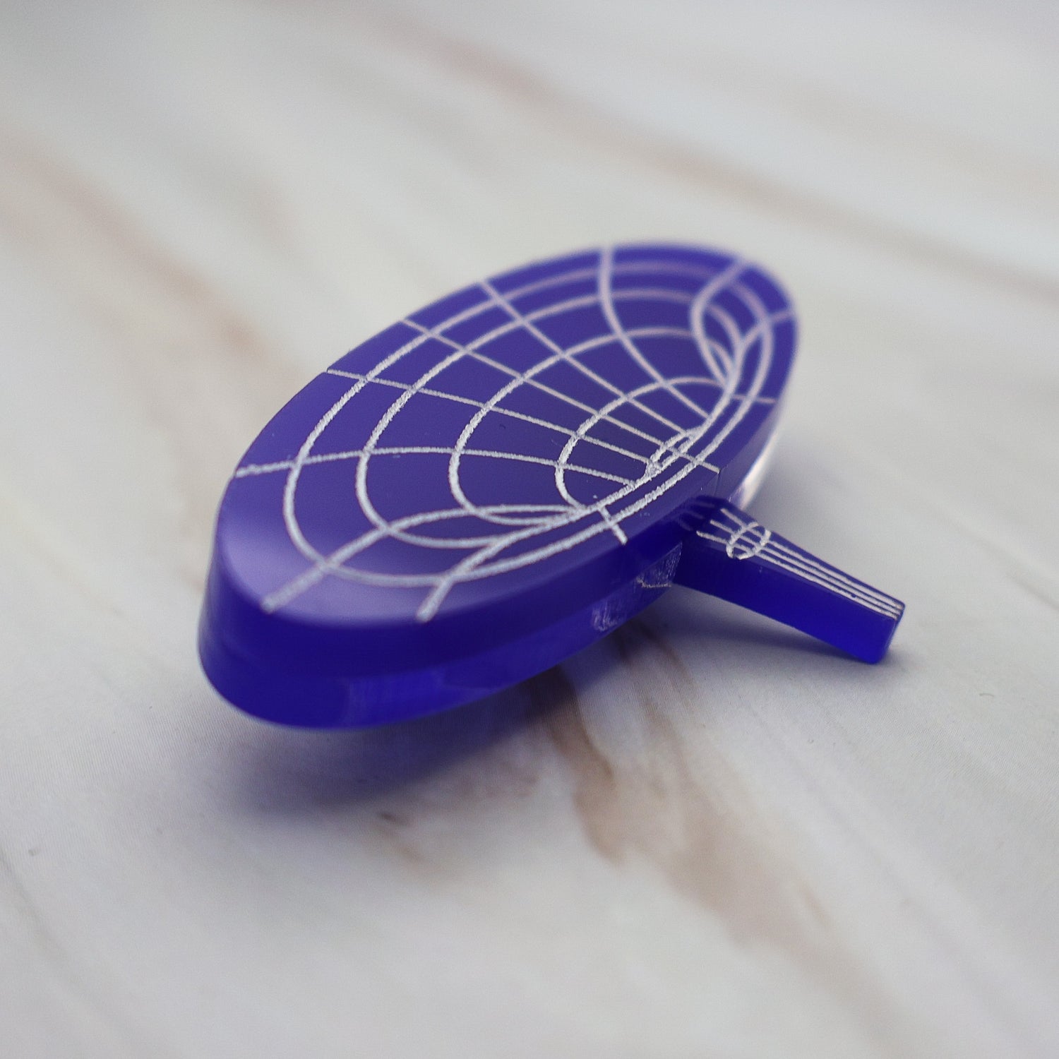 Angled view of dark blue wormhole brooch showing it's multilayered consruction.