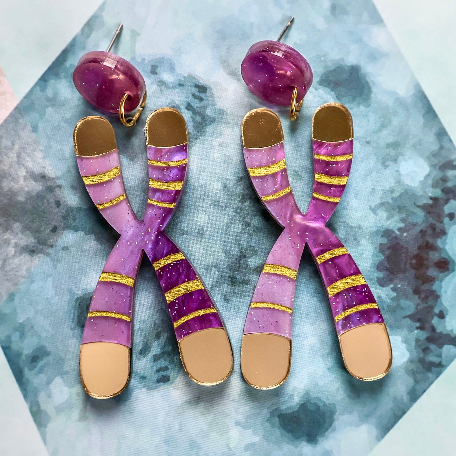 Front view of Chromosome Earrings in amethyst-toned sparkle acrylic with gold mirror telomeres and surgical steel posts