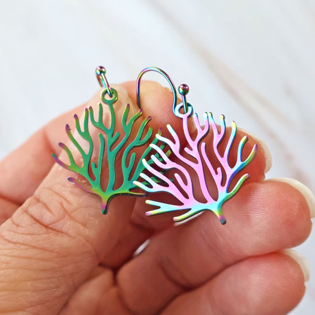 Small Colorful coral-shaped earrings held between fingers against a white background