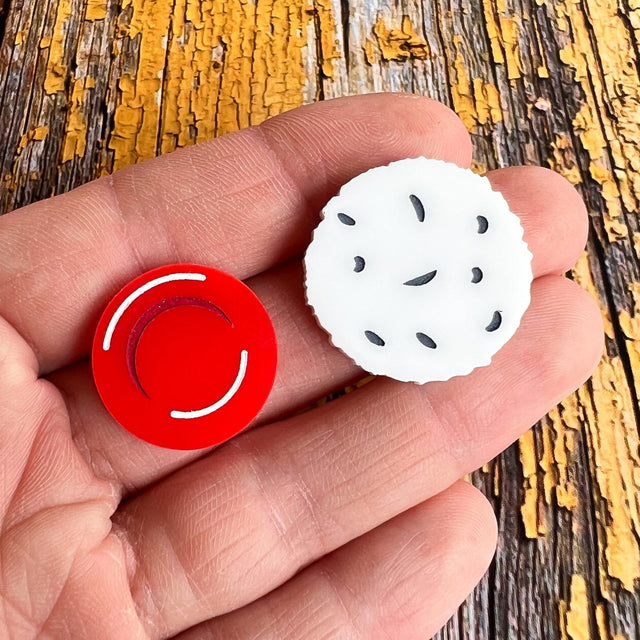 A pair of asymmetrical studs. One side is a red blood cell while the other side is a larger white blood cell. Laser cut, and handpainted from acrylic.