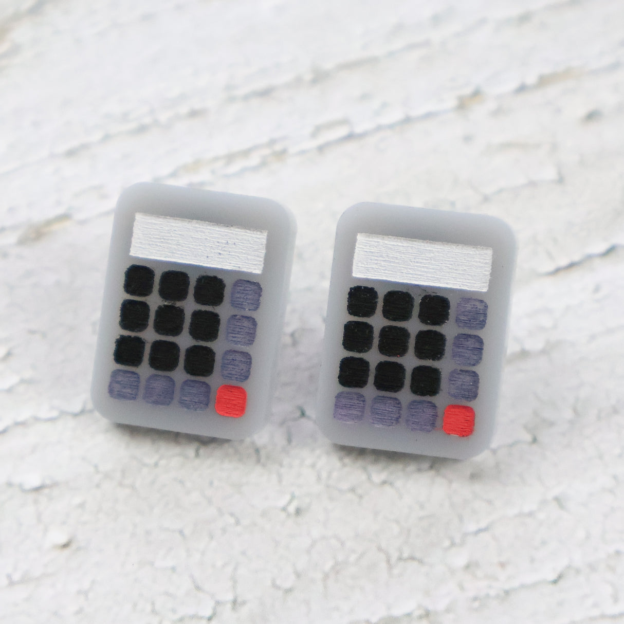 Calculator-shaped acrylic studs on a textured white surface