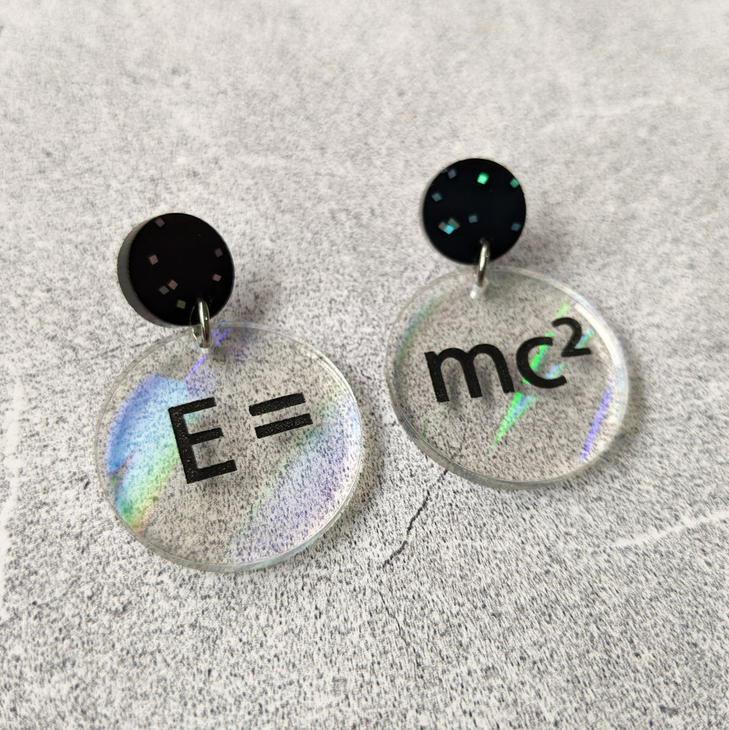 E =mc2 earrings, with black text engraved into holographic effect acrylic discs. Equation bridges both earrings. Black glitter earring toppers. Alternative view.