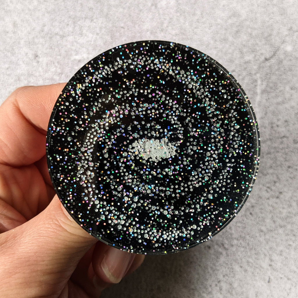 Laser Cut Acrylic Milky Way Galaxy Brooch 60mm diameter disc. Black with Glittery Stars. Close up view.